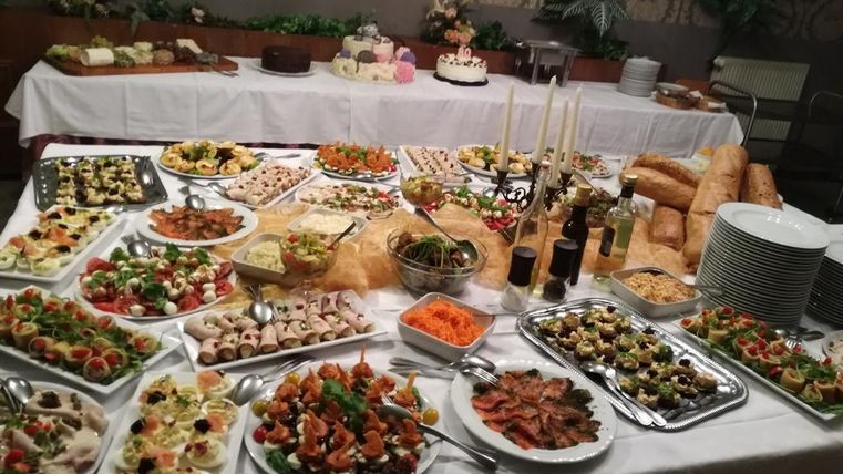 Ein reichhaltiges Buffet mit verschiedenen Vorspeisen, Salaten und Meeresfrüchten. In der Mitte befinden sich frische Brötchen und eine Auswahl an Desserts.