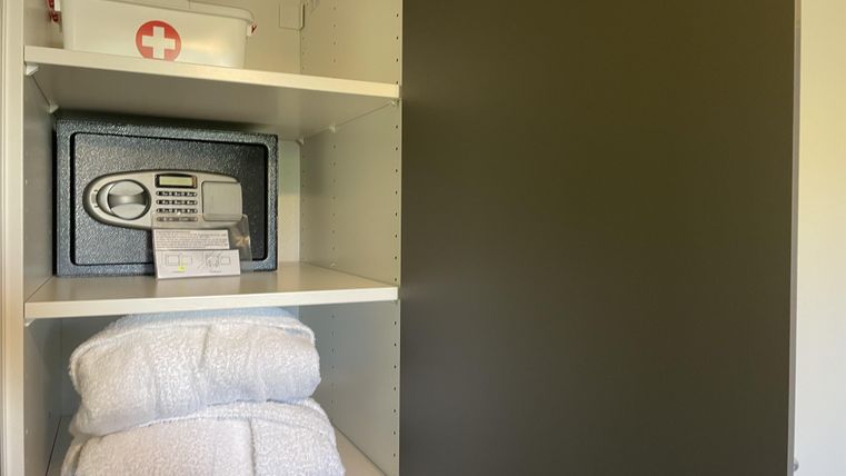 Ein Schrank mit frischen Handtüchern, einem Safe und einer Erste-Hilfe-Box. Alles ordentlich in Regalen aufgereiht.
