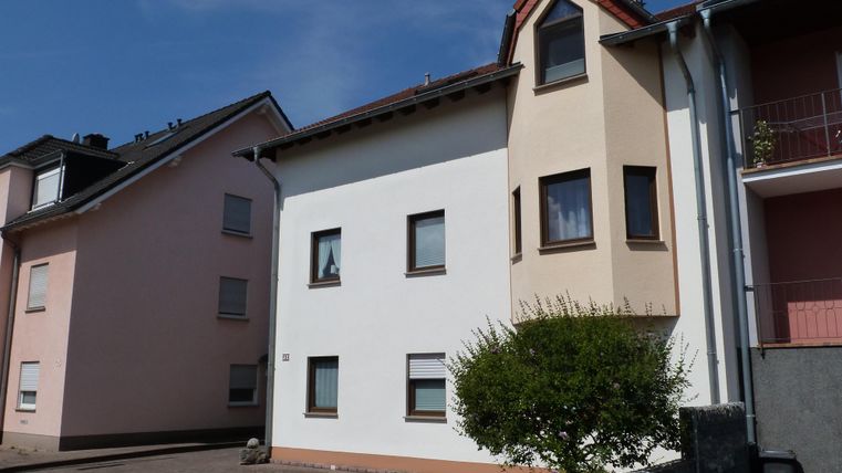 Ein modernes Wohnhaus mit einer hellen Fassade. Nebenan steht ein weiteres Gebäude in zartem Rosa.