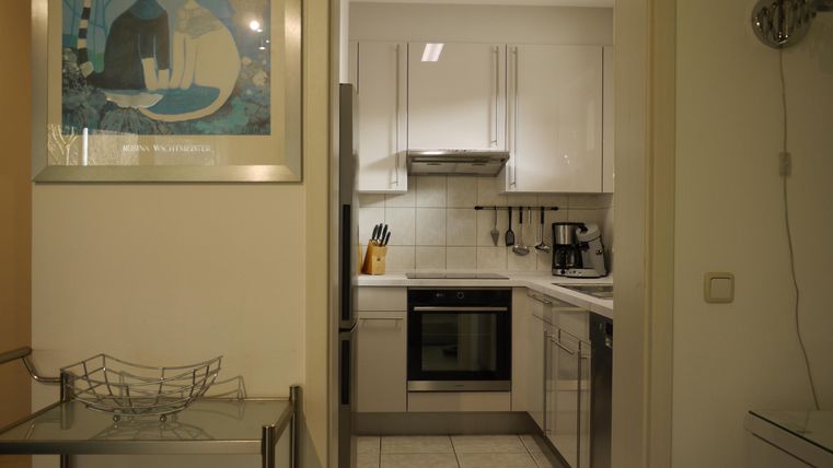 Eine moderne Küche mit weißen Schränken und verschiedenen Geräten. An der Wand hängt ein Kunstwerk.