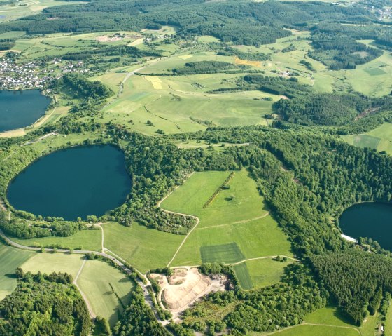 Vue a&eacute;rienne des Dauner Maare dans l'Eifel. Trois lacs circulaires sont entour&eacute;s de champs et de for&ecirc;ts verdoyants. Une petite agglom&eacute;ration est visible., &copy; Gesundland Vulkaneifel, D. Ketz