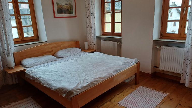 Ein gemütliches Schlafzimmer mit einem Doppelbett und großen Fenstern. Der Raum hat einen Holzfußboden und ist hell und einladend.