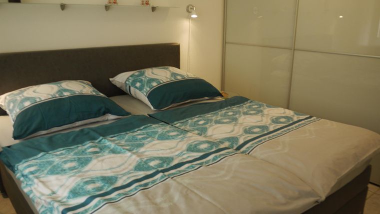 Ein gemütliches Schlafzimmer mit einem Doppelbett und hübscher Bettwäsche in Blau- und Beigetönen. Sanfte Beleuchtung sorgt für eine angenehme Atmosphäre.