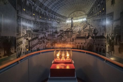 Ein historisches Museum mit einer beeindruckenden Wandmalerei und einer beleuchteten Vitrine. In der Vitrine befinden sich mehrere antike Lampen.