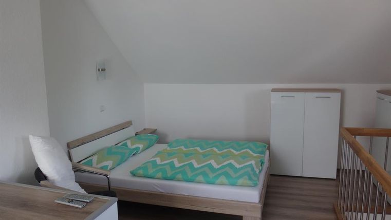 Ein einfaches Schlafzimmer mit einem Doppelbett und bunten Decken. Es gibt moderne Möbel und eine helle, freundliche Atmosphäre.