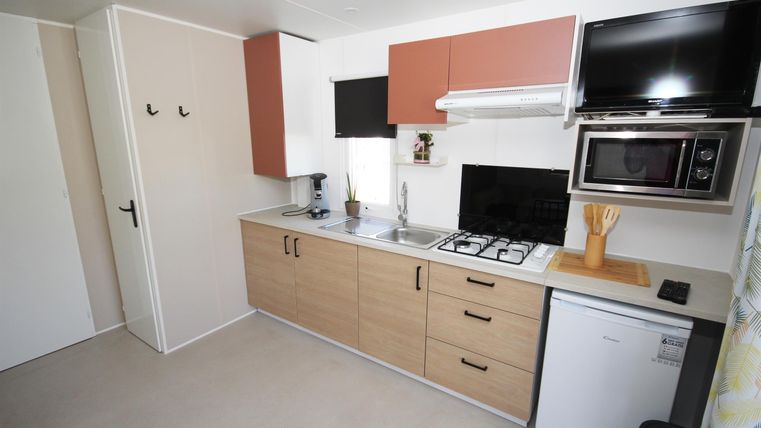 Eine moderne Küche mit Holzschränken und weißen Geräten. Sie ist gut ausgestattet mit einem Herd, einem Kühlschrank und einer Mikrowelle.