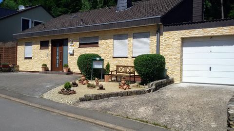 Ein hellgelbes Haus mit einer steinernen Fassade. Der Vorgarten ist gut gepflegt und hat eine gemütliche Bank.