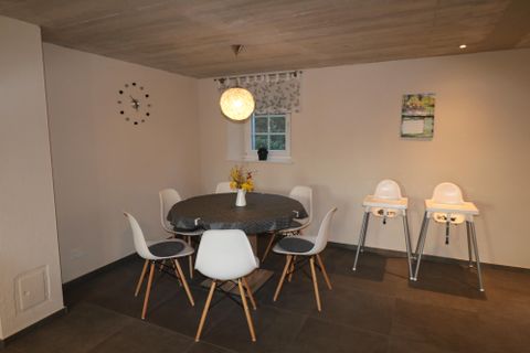 Ein gemütlicher Essbereich mit einem runden Tisch und weißen Stühlen. In der Ecke stehen zwei Hochstühle für kleine Kinder.