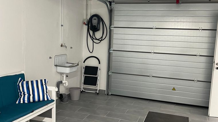 Die geflieste Garage ist mit einem automatischen Garagentor ausgestattet und verfügt außerdem über ein praktisches Waschbecken.