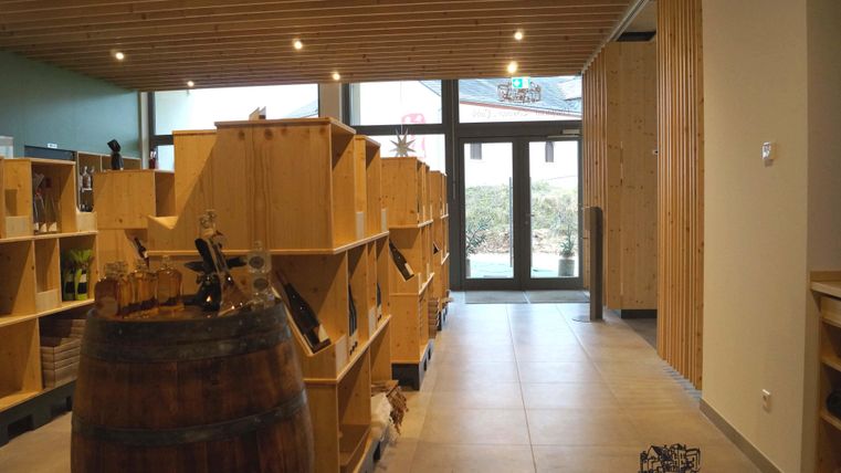 Ein modernes Geschäft mit Holzregalen und einer offenen Atmosphäre. Im Hintergrund sieht man große Fenster, die auf einen Außenbereich blicken.