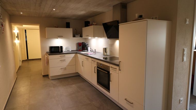 Eine moderne Küche mit weißen Schränken und einer eleganten Küchenzeile. Der Raum ist gut beleuchtet und hat einen schlichten, zeitgemäßen Look.