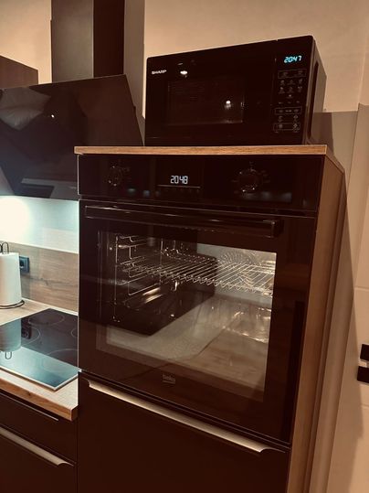 Eine moderne Küche mit einem Mikrowellenofen und einem integrierten Backofen. Beide Geräte sind in elegantem Schwarz mit digitaler Anzeige.
