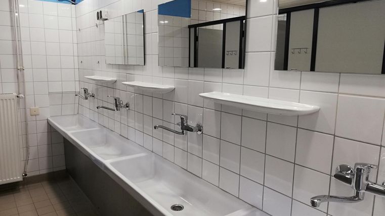 Ein sauberes Badezimmer mit mehreren Waschbecken und Spiegeln. Die Wände sind gefliest und die Beleuchtung ist hell.