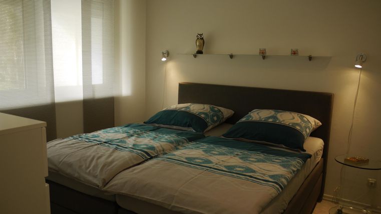 Ein gemütliches Schlafzimmer mit einem Doppelbett und bequemen Kissen. Helle Wände und Fenster sorgen für eine freundliche Atmosphäre.