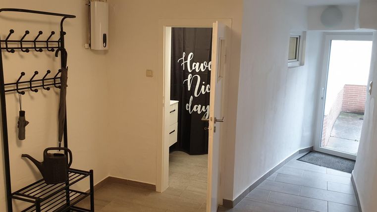 Ein moderner Eingangsbereich mit einer Garderobe und einem Stuhl. Durch die Tür ist ein heller Flur sichtbar.