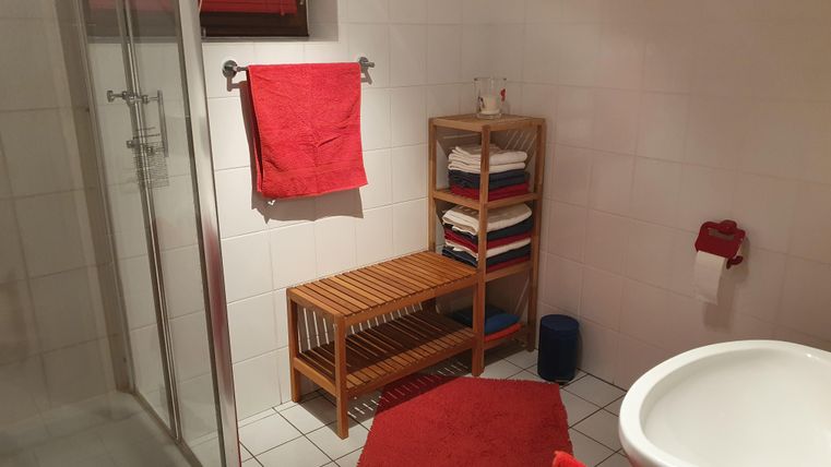 Ein modernes Badezimmer mit einer Dusche und einer Holzablage.