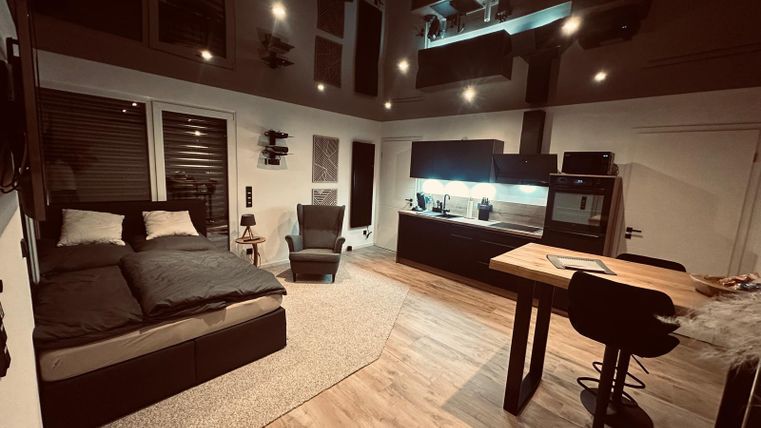 Ein modernes Zimmer mit einem gemütlichen Bett und einem kleinen Esstisch. Die Wände sind hell und die Atmosphäre ist einladend.