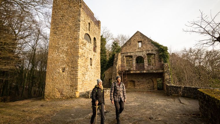 Zwei Personen wandern vor der Ruine der Prümer Burg.