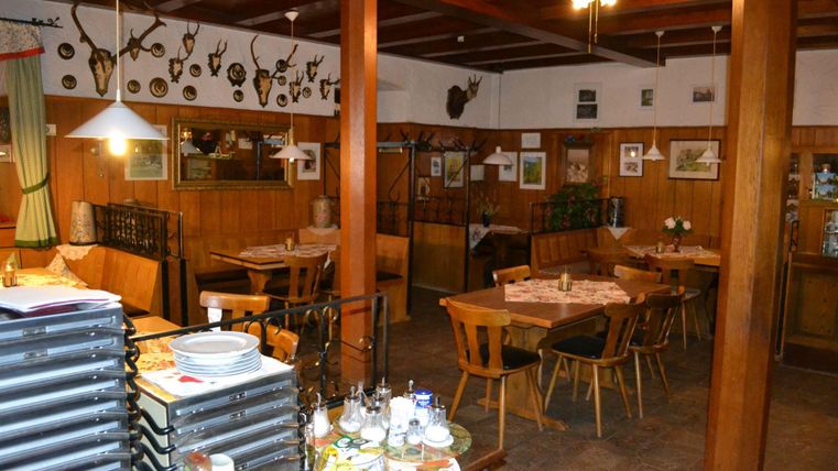 Ein gemütliches Restaurant mit Holzmöbeln und Jagdtrophäen an den Wänden. Es gibt gedeckte Tische und einen einladenden Raum für Gäste.