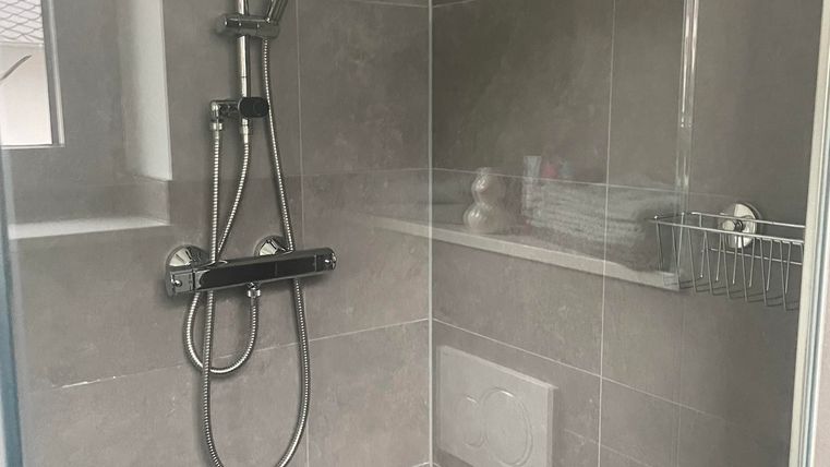 Das moderne Badezimmer verfügt über eine großzügige, ebenerdige Walk-in-Dusche mit eleganter Glasscheibe und komfortabler Regendusche.