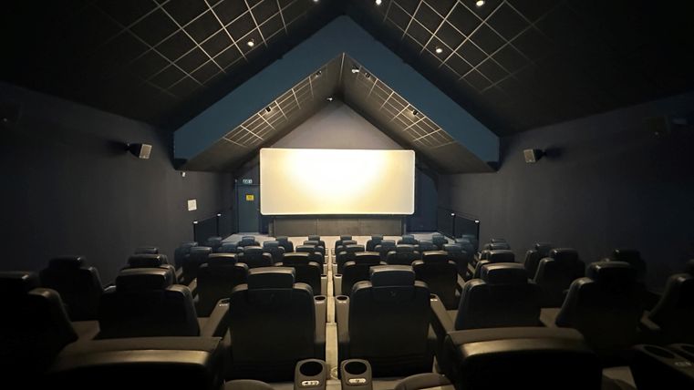 Ein leeres, modernes Kino mit bequemen Sitzen. Die Leinwand ist bereit für den Film.