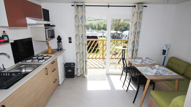 Eine moderne Küchenzeile mit einem Essbereich. Große Fenster bieten einen Blick nach draußen auf den Balkon.