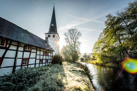 Fachwerkhaus und Kirche in Olef am Fluss bei Sonnenaufgang.
