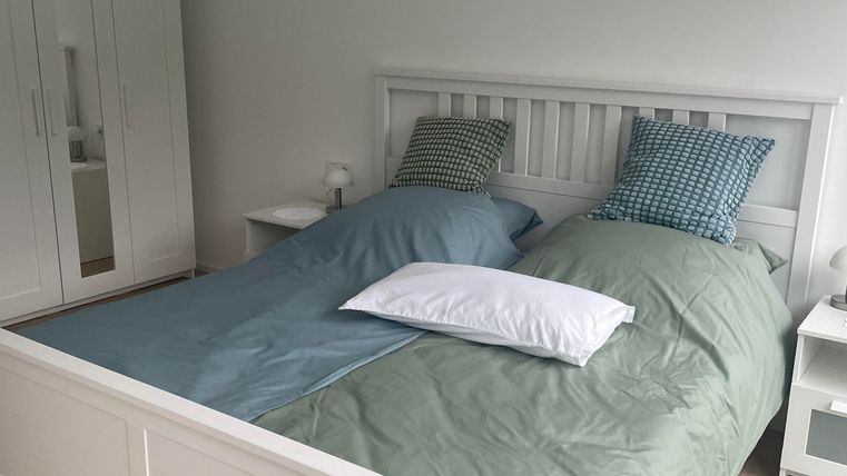 Das Schlafzimmer ist gemütlich und komfortabel eingerichtet. Es verfügt über ein großzügiges Doppelbett (1,80 m), einen Kleiderschrank mit Kleiderbügeln und Ablageflächen sowie eine Kommode. Zwei Nachttische mit Lampen sorgen für angenehmes Licht am Abend. Ein bequemer Sessel rundet die gemütliche Atmosphäre des Raumes ab.