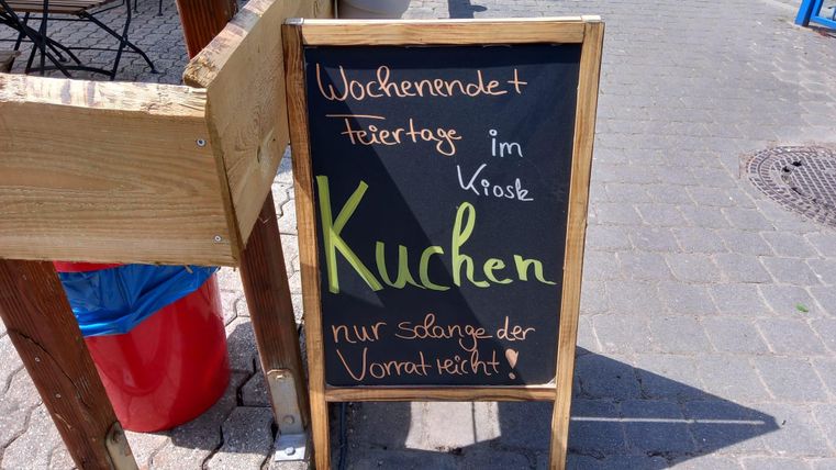 Ein Schild mit der Aufschrift „Kuchen“ für das Wochenende und Feiertage. Es weist darauf hin, dass nur solange der Vorrat reicht.