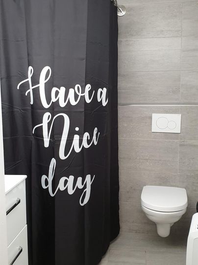 Ein modernes Badezimmer mit einer schwarzen Duschvorhang, auf dem "Have a Nice Day" steht. Es gibt eine Toilette und einen weißen Waschbecken.