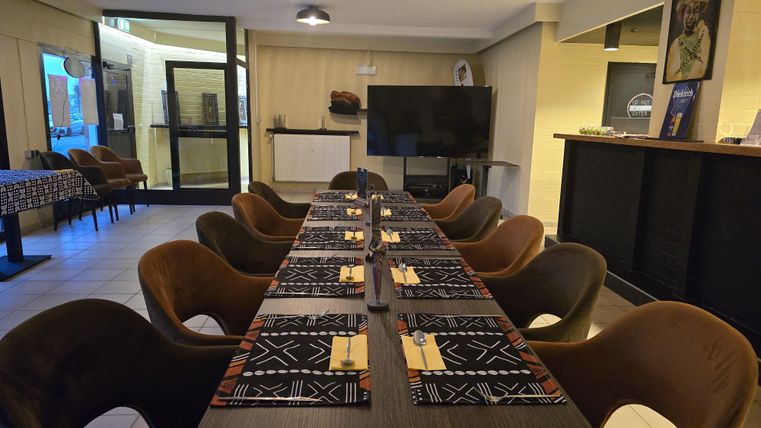 Ein eleganter Essbereich mit einem langen Tisch und Stühlen. Die Tischdecken sind stilvoll dekoriert und der Raum ist gut beleuchtet.