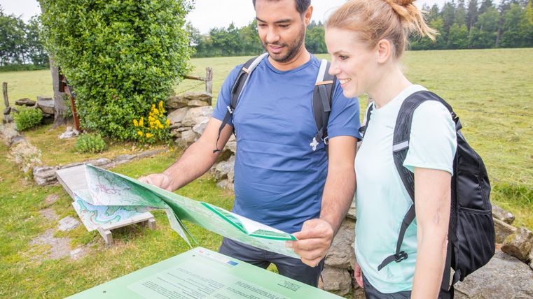 Zwei Personen betrachten eine Wanderkarte im Freien.