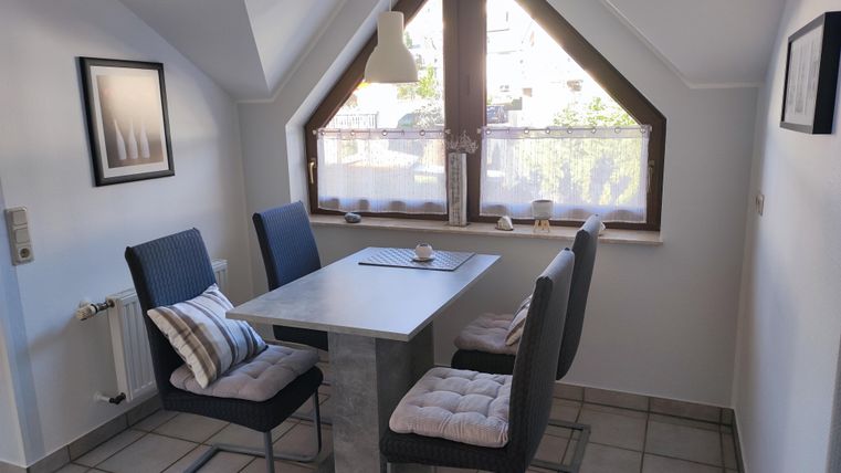 Ein heller Essbereich mit einem Tisch und vier Stühlen. Das Fenster lässt viel Tageslicht herein und bietet einen Blick nach draußen.