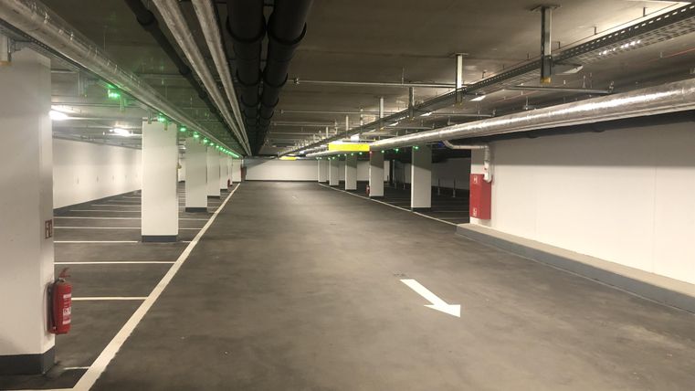 Eine leere Tiefgarage mit vielen Parkplätzen. Die Wände sind hell gehalten und die Beleuchtung ist gleichmäßig.