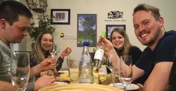 Eine gesellige Runde von vier Personen bei einem gemeinsamen Essen. Sie halten Gläser und Flaschen in der Hand und genießen den Moment.