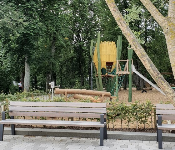 Playground in the Maximiner Wäldchen park in Bitburg with benches, climbing frame and slide, surrounded by trees and green spaces., © TI Bitburger Land